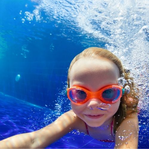 girl with googles swimming in a pool