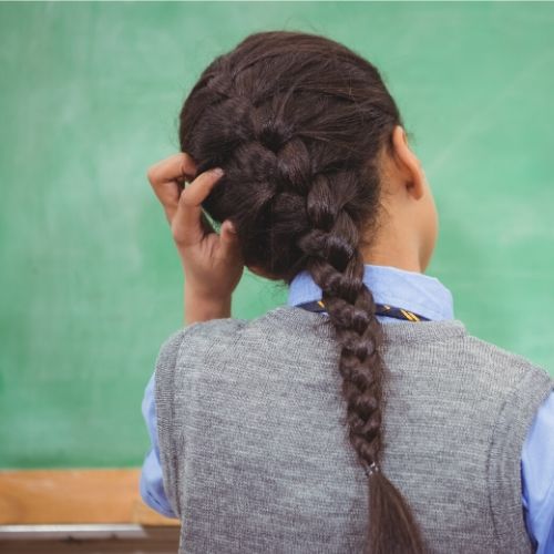 girls scratching her head, likely due to head lice infestation.