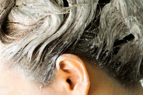 woman with white substance soaking in her hair, presumably cetaphil cleanser for head lice.