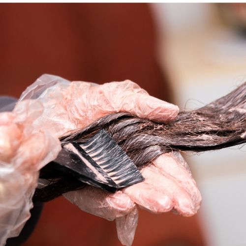 close up of gloved hands dying brown hair, presumably for head lice