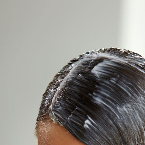 White substance in brunettes hair, presumably coconut oil for head lice