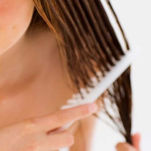 woman combing through hair, presumably after a lice treatment