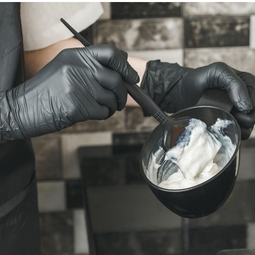 gloved hands mixing hair bleach or hair dye presumably to treat lice