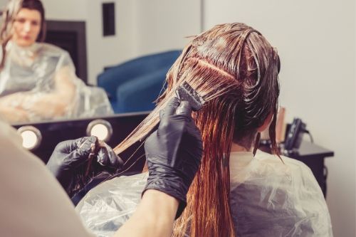 woman with red hair at a salon getting her hair dyed, presumably for head lice