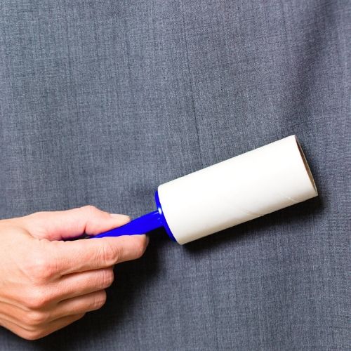 persons hand lint rolling a couch with lice