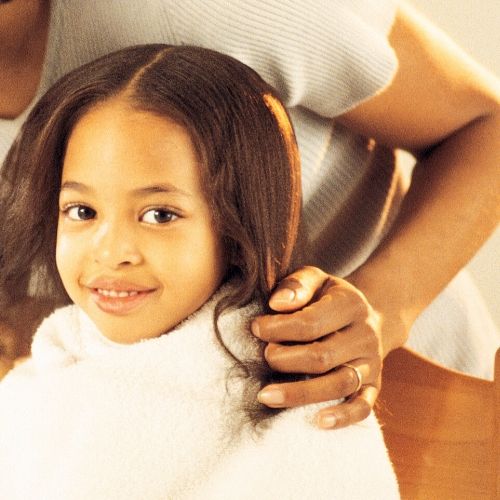 happy girl with towel on her shoulders, presumably read for a tea tree oil lice treatment