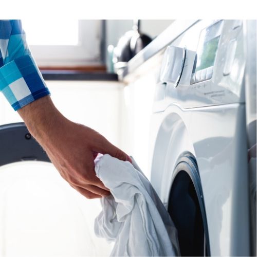 man placing clothes and carseat cover in dryer