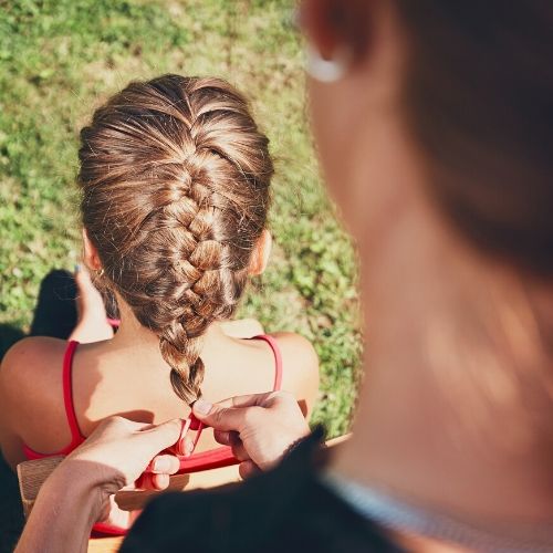 mother braiding her child's hair presumably for lice prevention