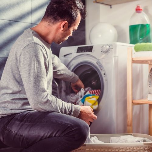 A man placing clothing in a dryer after lice