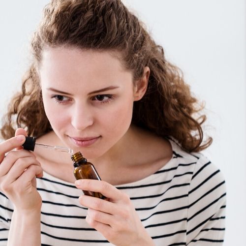 woman smelling a peppermint essential oil bottle, presumably to be used to prevent head lice