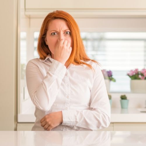 woman holding her nose presumably from the bad smell of a neem oil lice treatment