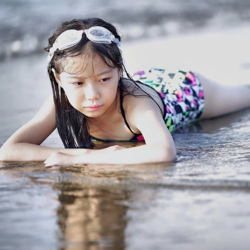young girl soaking hair in sea water on the beach