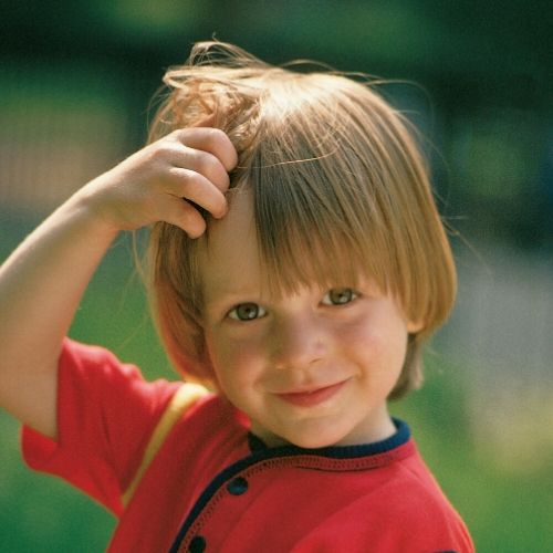 small boy itching his head, presumably with lice after swimming