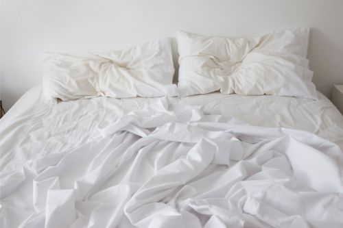 A messy bed with two pillows.