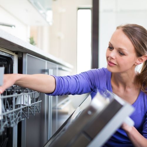 A woman loading a dishwasher with lice infested brushes and combs