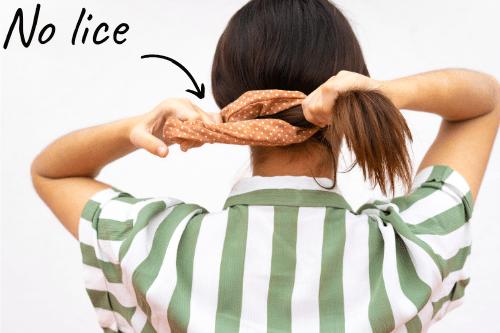 woman tying her hair in a scrunchie to prevent head lice