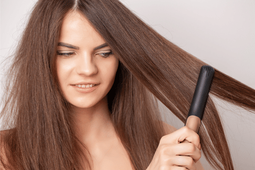 woman flat ironing her hair to prevent lice