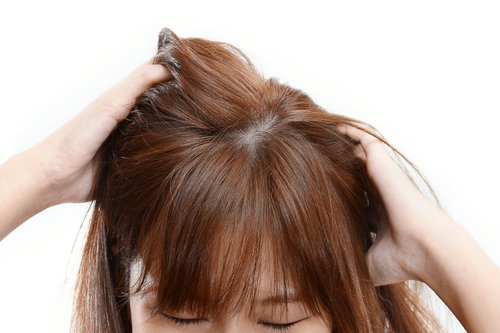 woman itching her scalp, presumably because she has lice