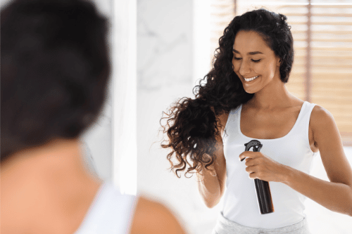 woman spraying her hair withconditioning lice spray