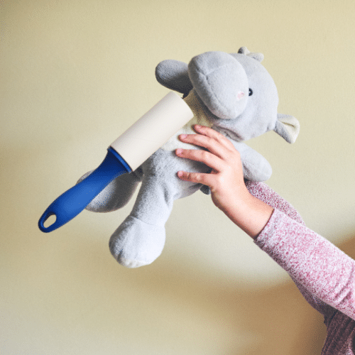 stuffed animal hippo being cleaned for lice using a sticky tape lint roller