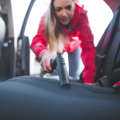 woman cleaning and vacuuming carseats from lice